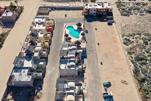 An aerial view of a residential area with a swimming pool surrounded by houses and a road.