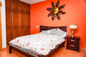 A bedroom with a bed, nightstand, and a wall-mounted sun decoration.