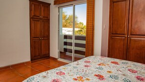 Un dormitorio con cama, armario de madera y puerta corredera de cristal que da a un balcón.