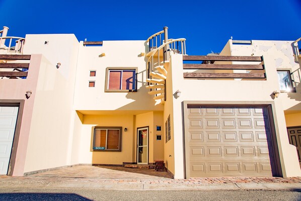 A two-story house with a spiral staircase, a garage, and a small front porch. - Bella Vista 6 (3 Bed 2.5 Bath By FMI Rentals) (Puerto Peñasco)