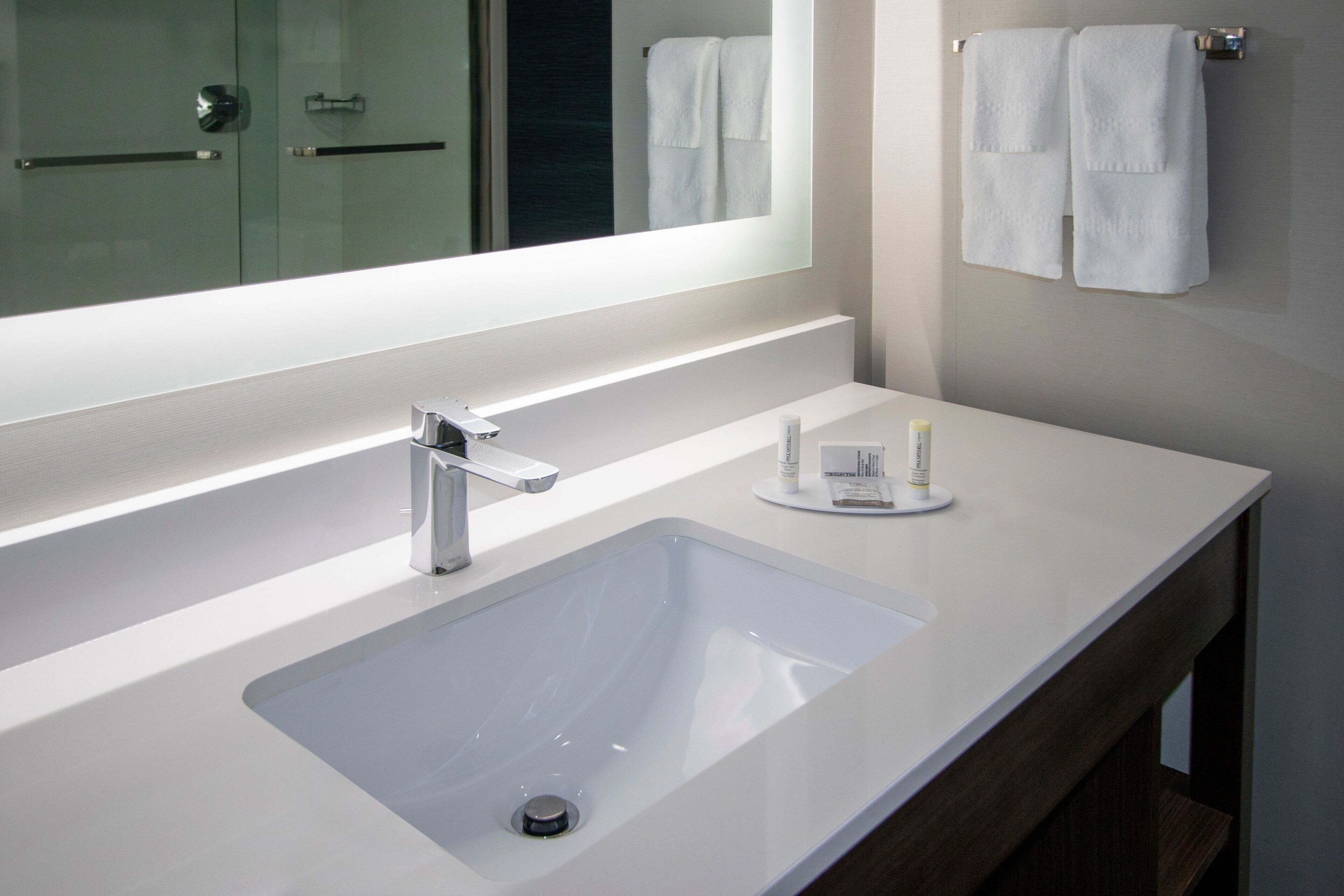 A modern bathroom with a white sink, a mirror, and a towel rack.