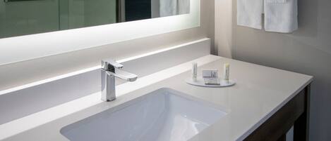 A modern bathroom with a white sink, a mirror, and a towel rack.