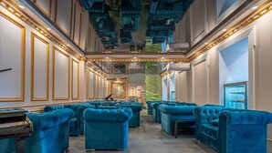 A luxurious hotel lobby with plush blue sofas arranged in rows, a grand staircase, and a modern ceiling design. - 5 Star Apart Hotel (Tbilisi)
