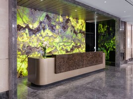 A reception desk with a marble wall backdrop and a vase of white flowers.