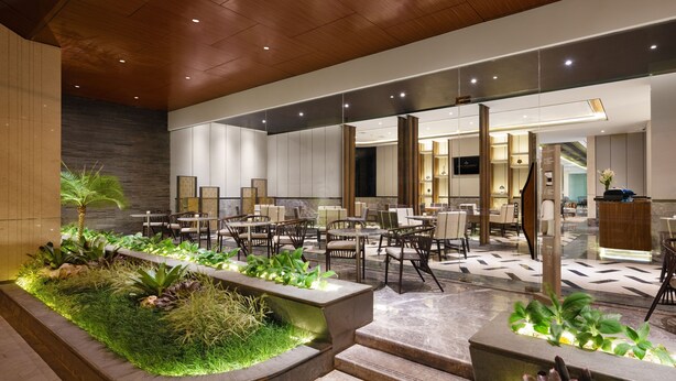 A modern hotel lobby with a reception desk, seating area, and a decorative garden. - Royal Malioboro Yogyakarta by Aston (Yogyakarta)