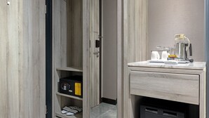 A modern bathroom with a wooden vanity, a shower area, and a small refrigerator. - Royal Malioboro Yogyakarta by Aston (Yogyakarta)