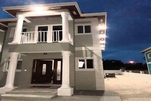 A two-story house with a balcony, a front door, and a small porch area.