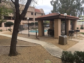 A covered outdoor seating area with a pool in the background. - ASU Arizona State University Tempe Executive Condo (Tempe)