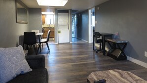 Un salon moderne avec un canapé, une table à manger et un coin cuisine à l’arrière-plan.