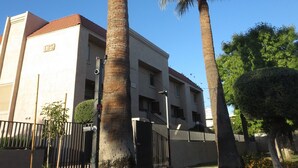 Un bâtiment avec deux palmiers devant, un ciel bleu dégagé et une pelouse bien entretenue.