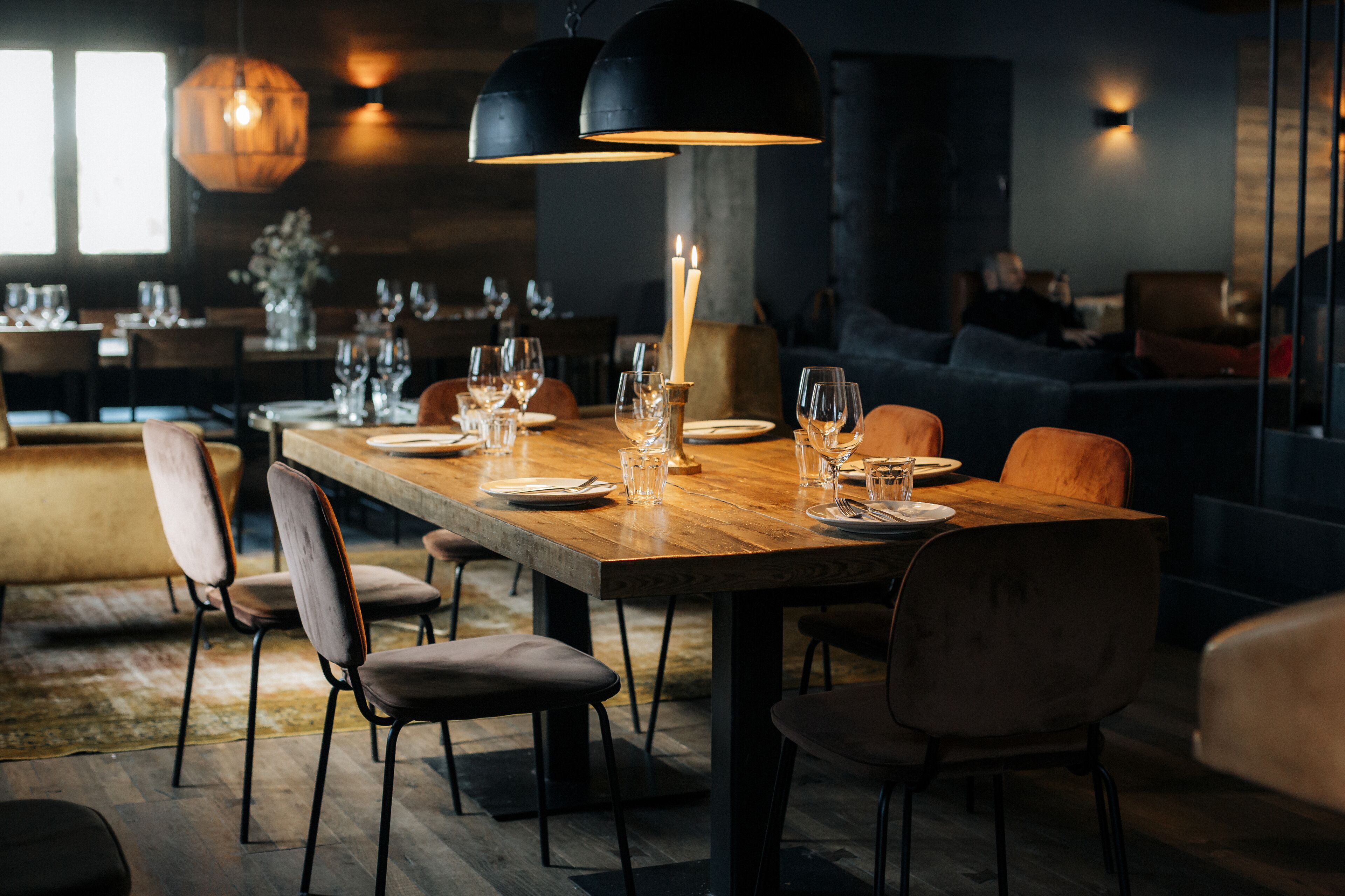 Un espace repas avec une longue table en bois, dressée pour six personnes, entourée de chaises rembourrées.