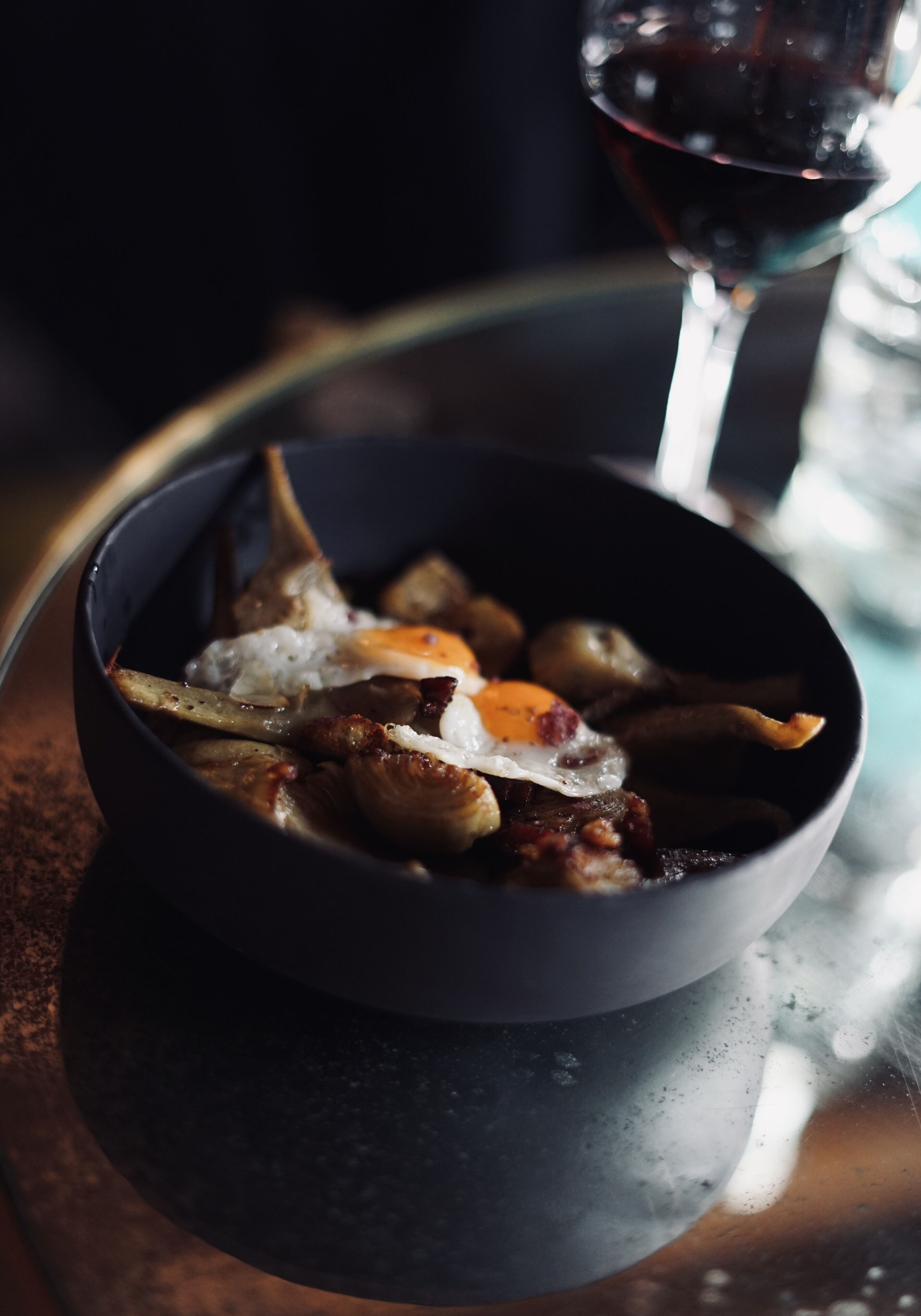 Un plato de comida con una copa de vino tinto sobre una mesa.
