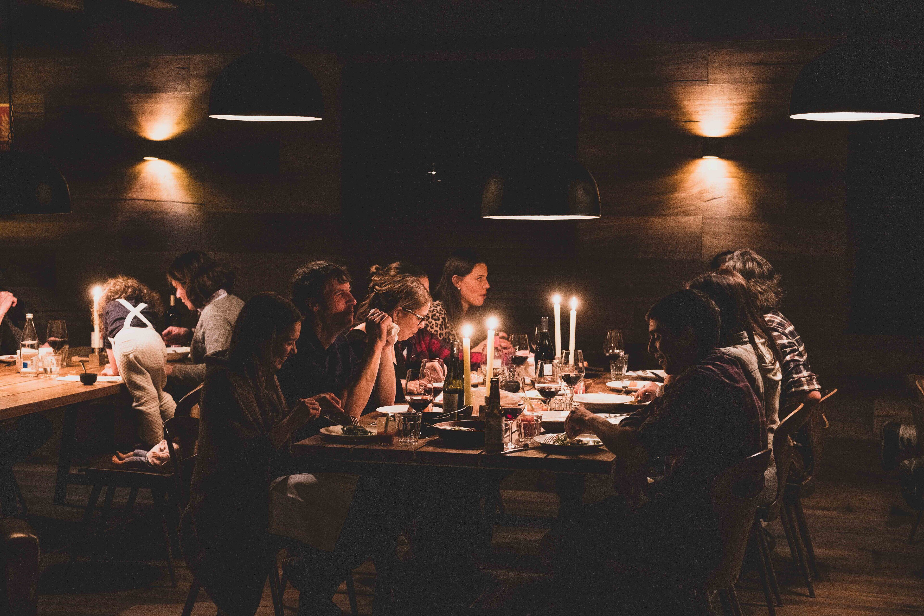 A dimly lit restaurant with wooden walls and tables set for dining.