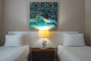 A hotel room with two beds, a nightstand with a lamp, and a painting on the wall.
