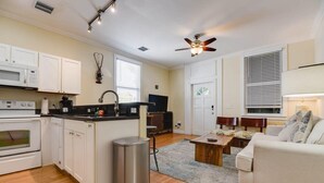 A compact living space with a kitchenette, a dining area, a sofa, and a ceiling fan. - The Mesa House - One block from Duval St (Key West)