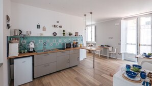 Una cocina moderna con una isla central, un comedor con mesa y sillas, y vistas al exterior a través de amplios ventanales.