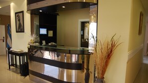 A reception desk with a glass top, a black counter, and a vase with dried plants. - Gran Hotel Laserre (Río Grande)