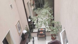A spacious balcony with a tiled floor, two cushioned chairs, a small table, and several potted plants. - Gran Hotel Laserre (Río Grande)