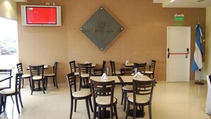 A hotel lobby with multiple tables and chairs, a television mounted on the wall, and a sign indicating the exit. - Gran Hotel Laserre (Río Grande)