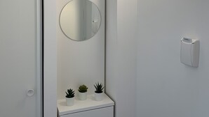 A modern bathroom with a white sink, a round mirror, and a wall-mounted light fixture. - Moov'Appart Hotel Clichy (Clichy)