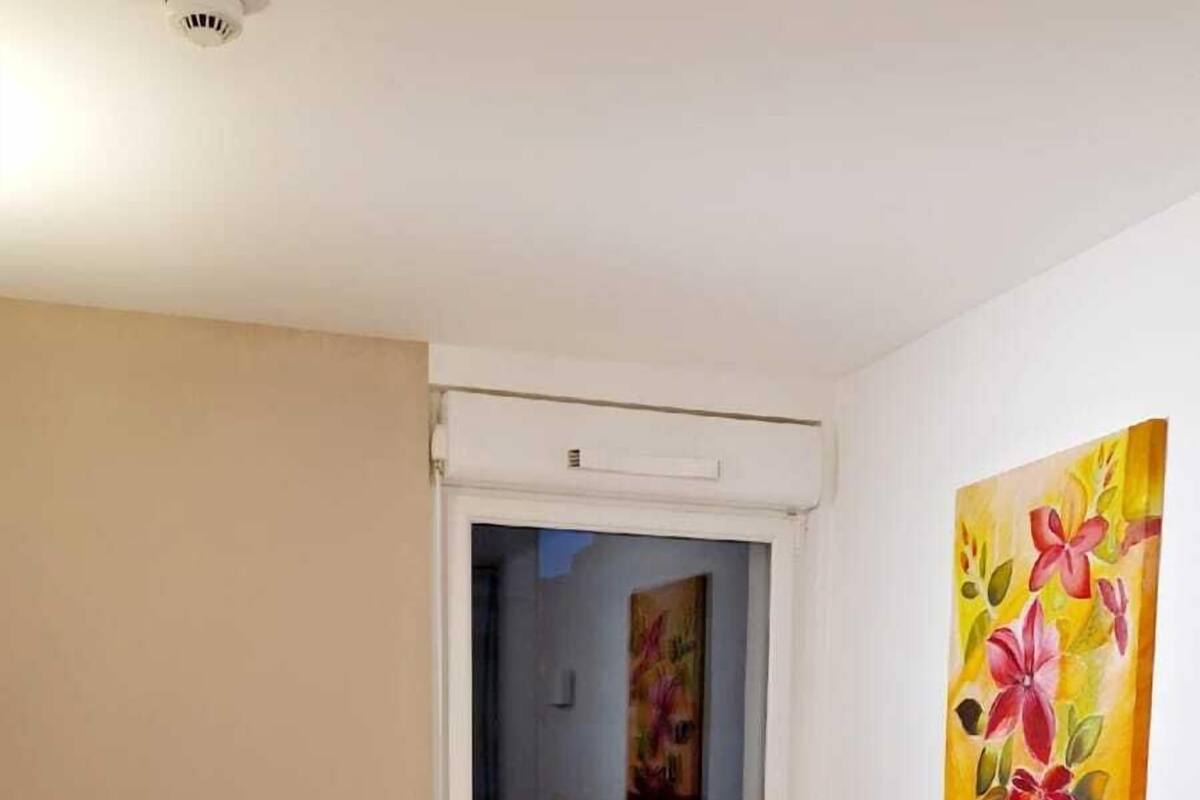 A hotel room with two beds, a window with a view, and a painting on the wall.