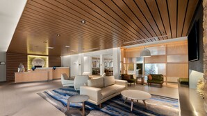 A spacious, modern interior with a wooden ceiling, a reception area, a seating area with a sofa and coffee table, and a large window providing natural light. - Fairfield Inn & Suites by Marriott Brooksville Suncoast Parkway (Spring Hill)