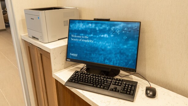 A desktop computer with a monitor displaying a welcome message, a keyboard, and a mouse on a counter. - Fairfield Inn & Suites by Marriott Brooksville Suncoast Parkway (Spring Hill)