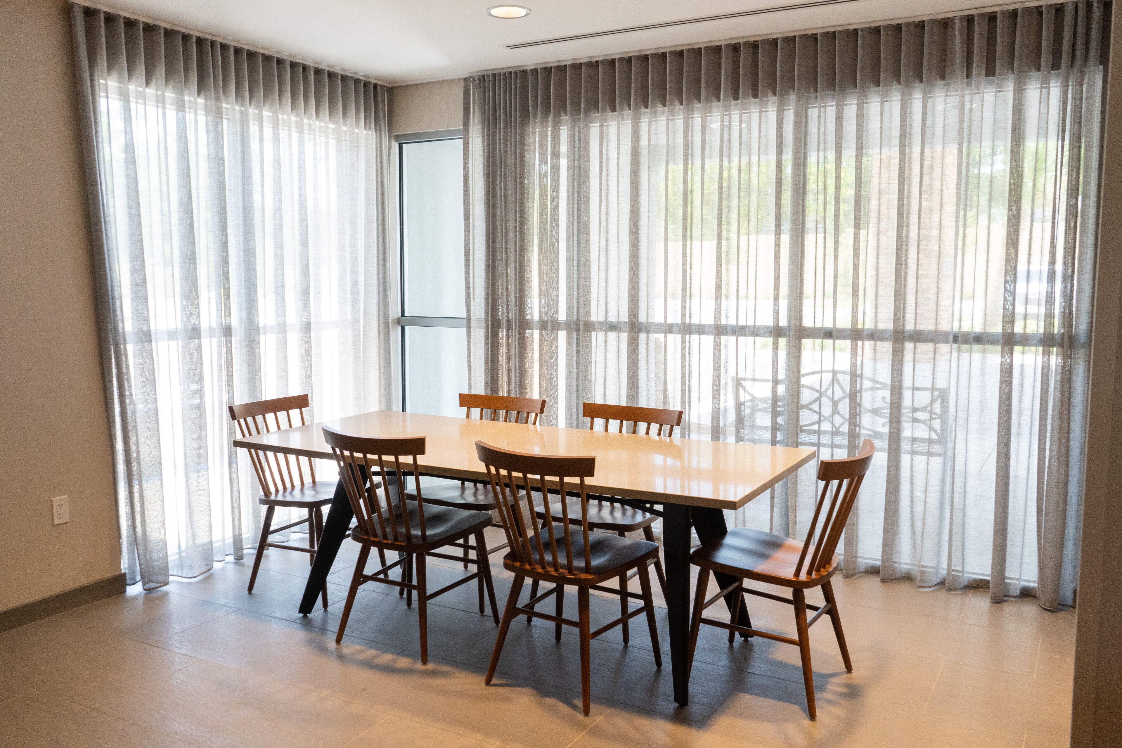 A dining area with a rectangular table and six wooden chairs.