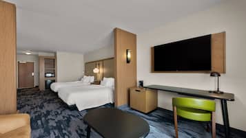 Quarto de hotel com cama, escrivaninha, cadeira e televisão fixada na parede.
