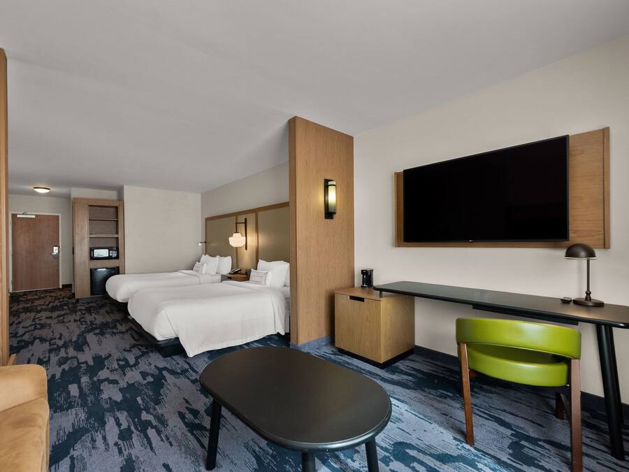 A hotel room with a bed, desk, chair, and a TV mounted on the wall.