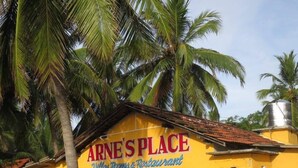 Un bâtiment jaune sur lequel on peut lire l’inscription suivante : « ARNE’S PLACE, villas, chambres et restaurant ».