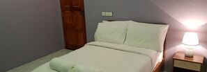A bedroom with a bed, a nightstand, a lamp, and a wooden door.