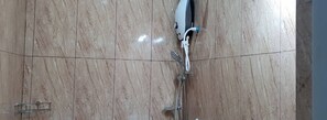 A bathroom with a marble floor, a white shower unit, and a visible showerhead.