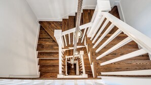 A staircase with white railings and wooden steps, leading to a landing with a hanging light fixture. - Carlton Landing-Spacious home on Boulevard (Eufaula)