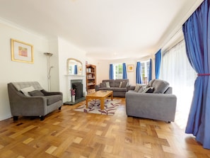 A living room with a fireplace, two sofas, a coffee table, and a bookshelf. - Bay House, Aldwick Bay  - sleeps 7 guests  in 4 bedrooms (Bognor Regis)