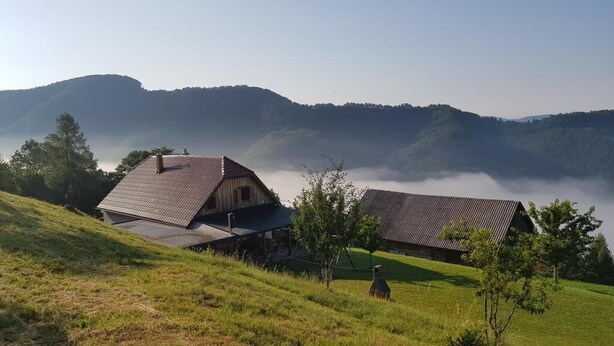 A rural landscape with two barns and a house on a grassy hill. - Vacation House Donacka Gora (Rogatec)