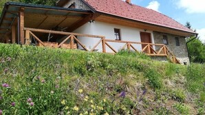 A rustic stone building with a red-tiled roof, wooden balcony, and a covered porch. - Vacation House Donacka Gora (Rogatec)