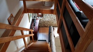 A wooden staircase leading to a living area with a sofa and a coffee table. - Vacation House Donacka Gora (Rogatec)