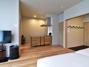 A modern hotel room with a wooden floor, a bed, a TV, a minibar, a wooden dresser, and a wardrobe. - Standard room 202  1LDK Nopets / Sambu-gun Chiba (Sambu-gun)