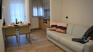 A compact living space with a dining area, kitchenette, and a sofa. - Albergo Pieve (Ledro)