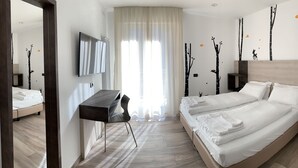 A modern hotel room with a large bed, a desk, and a mirror. - Albergo Pieve (Ledro)