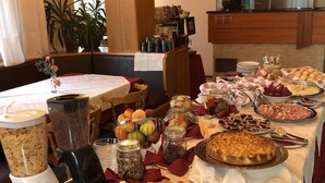 A buffet table with various food items, including fruits, pastries, and a cake. - Albergo Pieve (Ledro)