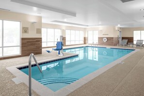 An indoor swimming pool with clear water, a blue chair, and a lifeguard chair. - TownePlace Suites by Marriott Cincinnati Fairfield (Fairfield)
