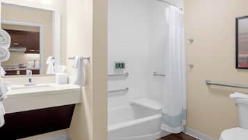 A bathroom with a sink, mirror, toilet, and shower area.
