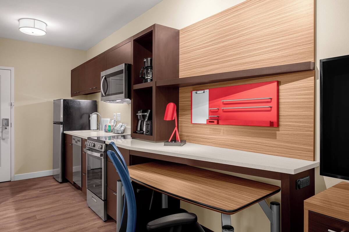 A modern kitchen with built-in appliances, a wooden countertop, and a red appliance drawer.