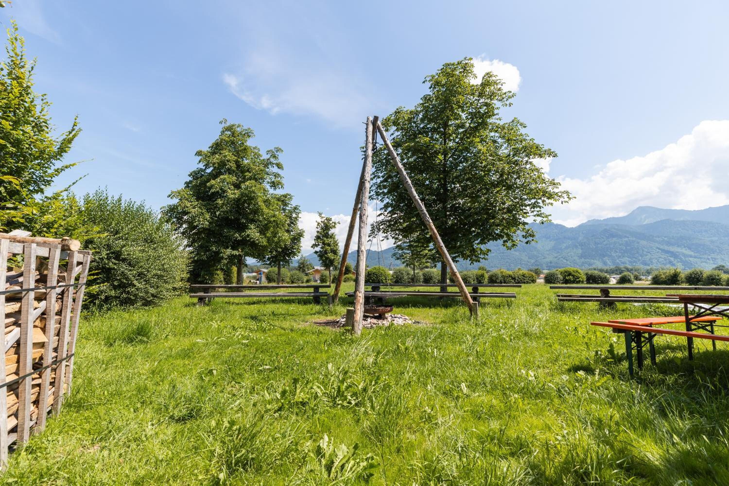 A grassy outdoor area with picnic tables and a wooden structure.