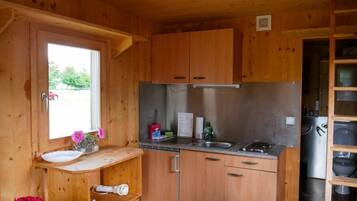 Cocina compacta con armarios de madera, un lavamanos de acero inoxidable y una ventana que proporciona luz natural.