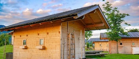Una cabaña de madera con techo inclinado, una escalera y un pequeño porche.