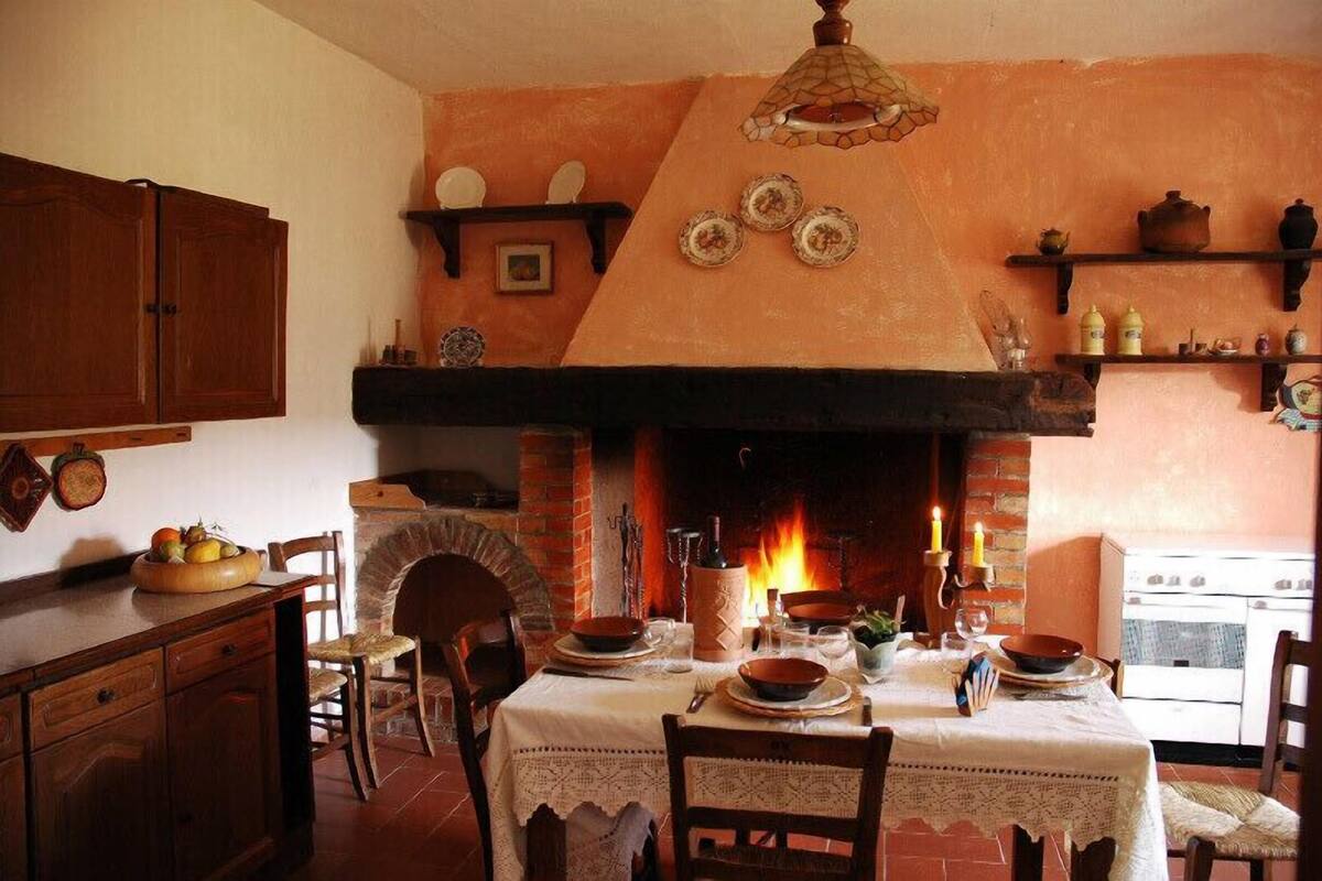 Una cocina tradicional con chimenea de ladrillo, armarios de madera y una mesa de comedor para cuatro.