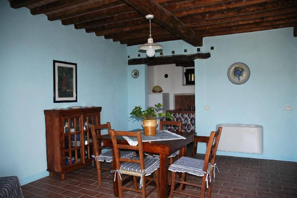 Un comedor con una mesa y sillas de madera, un ventilador de techo y un armario con puertas de vidrio.
